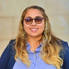 woman with tinted eyeglasses, long hair, wearing a blue shirt